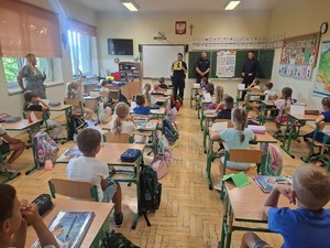 umundurowani policjanci w klasie przed siedzącymi dziećmi