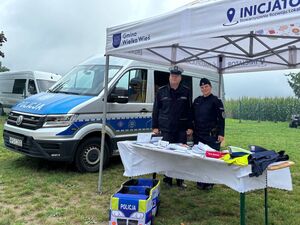 umundurowana policjantka i policjant na stoisku policyjnym obok radiowóz