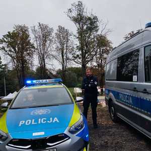 umundurowany policjant stojący pomiedzy radiowozami