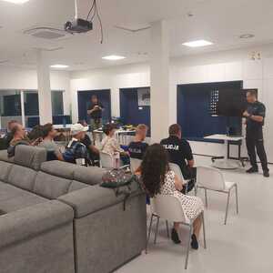 umundurowany policjant prowadzący prelekcję przed nim siedzący mieszkańcy