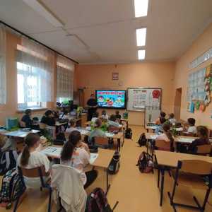 umundurowana policjantka w klasie przed nią siedzące dzieci w ławkach