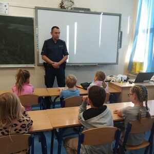 umundurowany policjant w klasie przed nim siedzą uczniowie