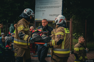 policjant w mundurze i strażacy podczas udzielania pomocy w czasie ćwiczeń ewakuacji przedszkola