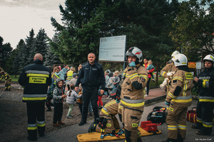umundurowany policjant i strażacy podczas ćwiczeń z tyłu stoją dzieci