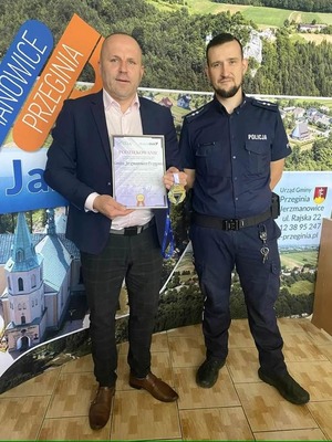 umundurowany policjant i mężczyzna trzymający w rękach podziękowania