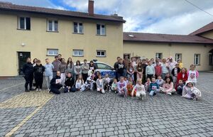 umundurowana policjantka stojąca z uczniami przed szkołą z tyłu oznakowany radiowóz policyjny