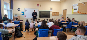 umundurowany policjant w klasie przed nim siedzą uczniowie