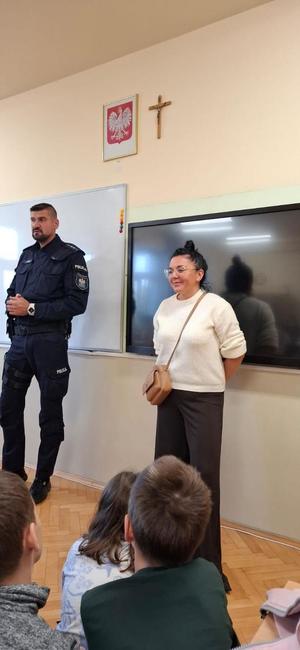 umundurowany policjant obok niego nauczycielka w klasie podczas pogadanki