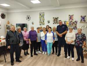 umundurowany funkcjonariusz Policji stoi na sali wraz z seniorami