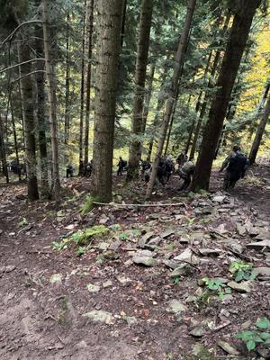 uczniowie w mundurach schodzą z góry w lesie