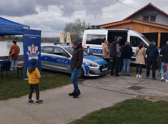 dwa radiowozy oznakowane obok ludzie obserwujący pokaz