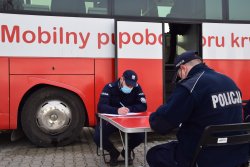 policjanci wypełniają dokumenty przed krwiobusem