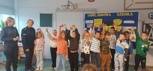 umundurowane policjantki na wspólnym zdjęciu z dziecmi które z rączkami do góry trzymają odblaski
