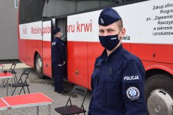 policjant stojący przy krwiobusie