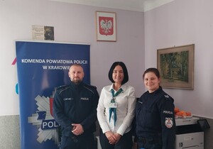 umundurowani policjanci z kobietą za nimi baner komendy