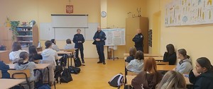 trzech umundurowanych policjantów na sali szkolnej z uczniami