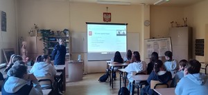 umundurowana policjantka, ekran z prezentacją, uczniowie siedzący w ławkach