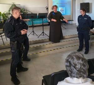 umundurowani policjanci przed nimi ekran z hasłem bezpieczny senior