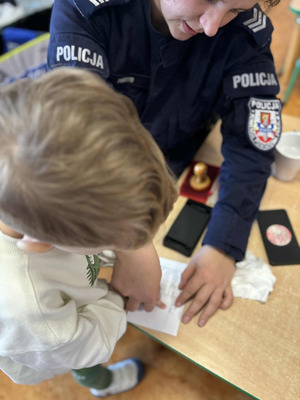 umundurowana policjanta pobiera od chłopca odciski palców
