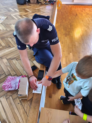 umundurowany policjant pobiera od dziecka odciski palców