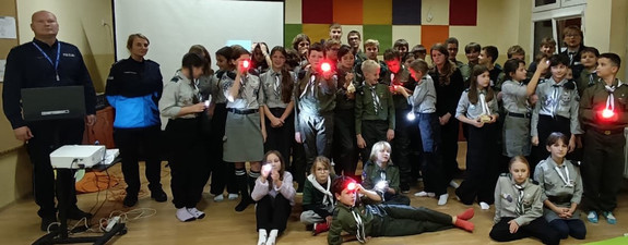 umundurowani policjanci na wspólnym zdjęciu z harcerzami z włączonymi lampkami