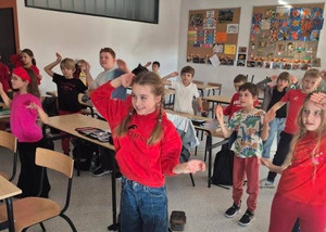 dzieci stoją na sali unoszą ręce do góry