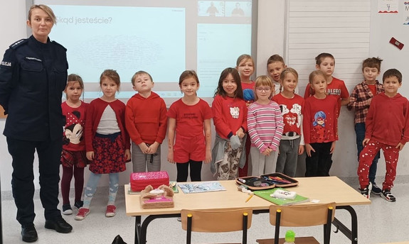 umundurowana policjantka na wspólnym zdjęciu z dziećmi ubranymi na czerwono