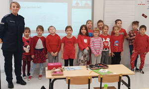 umundurowana policjantka na wspólnym zdjęciu z dziećmi ubranymi na czerwono