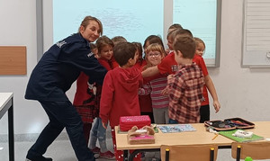 umundurowana policjantka w otoczeniu dzieci ubranych na czerwono