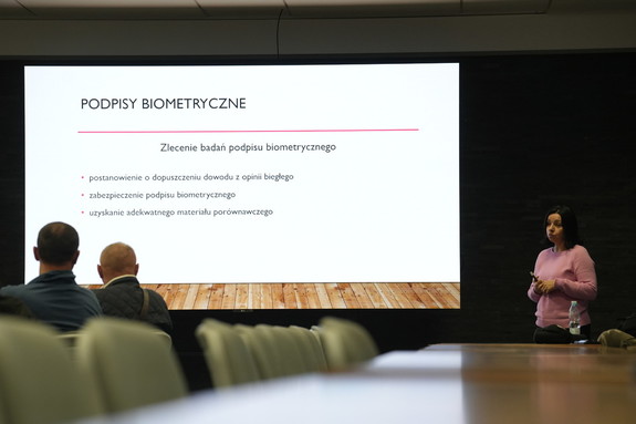 ekran z prezentacją obok kobieta na sali wykładowej