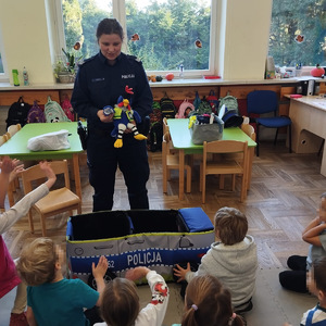 umundurowana policjantka z maskotką przed nią siedzą dzieci