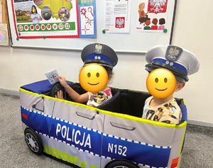 dzieci w czapkach policyjnych siedzą w radiowozie