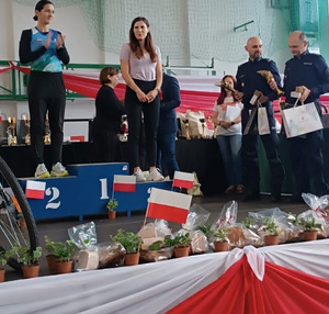 umundurowani policjanci wręczają puchary i nagrody obok dwie kobiety