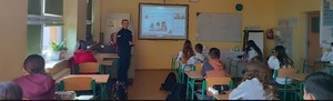 umundurowana policjantka na sali lekcyjnej przed nią ekran z prezentacją