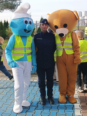 umundurowana policjantka obok niej osoby przebrane za maskotki