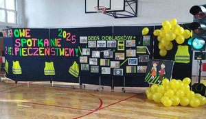 sala gimnastyczna na niej tablica z odblaskowymi pracami, żółte balony, sygnalizator drogowy