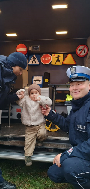 umundurowani policjanci z małym chłopcem wychodzącym z radiowozu