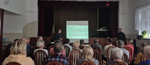 umundurowana policjantka obok niej mężczyzna seniorzy siedzą na krzesłach