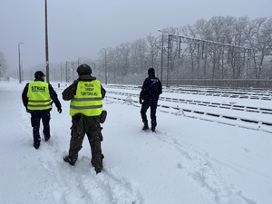 umundurowani policjanci idą wzdłuż torów kolejowych