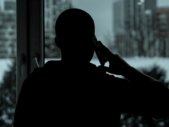 postać człowieka przy oknie z telefonem przy uchu