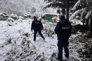 dwóch umundurowanych policjantów idzie w kierunku altany