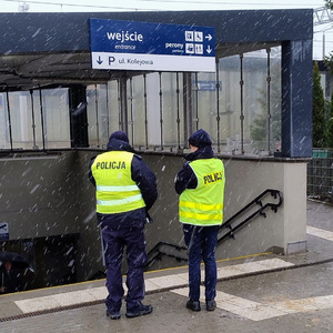 dwóch umundurowanych policjantów stoi przy wejściu na peron
