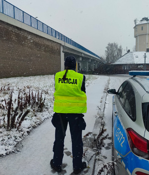 umundurowana policjantka stoi obok oznakowanego radiowozu przy wiadukcie