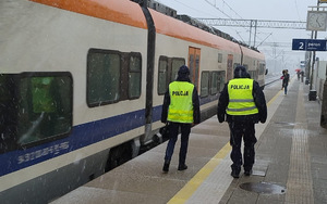 umundurowany patrol Policji idzie na peronie obok pociąg