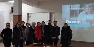 umundurowani policjanci na wspólnym zdjęciu z seniorami za nimi ekran