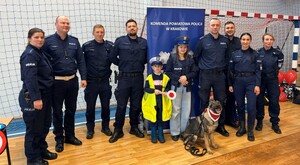 umundurowani policjanci z dziećmi w strojach policyjnych obok nich pies służbowy