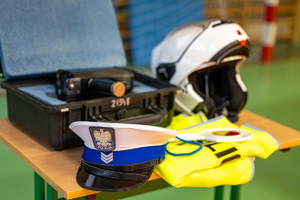 czapka policyjna, kask i kamizelka odblaskowa leżące na stole