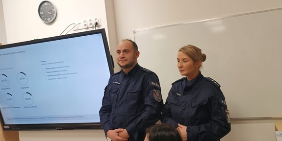 umundurowani policjanci stoją pod tablicą w klasie podczas spotkania
