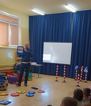 policjant w mundurze pokazuje dzieciom znaki drogowe