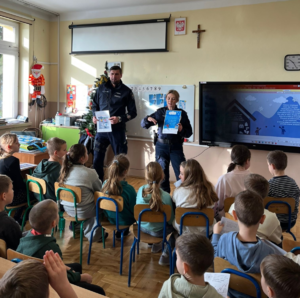 umundurowani policjanci stoją w sali przed nimi siedzą dzieci